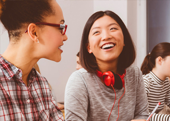Two young women enjoying social interaction as they work at their computers